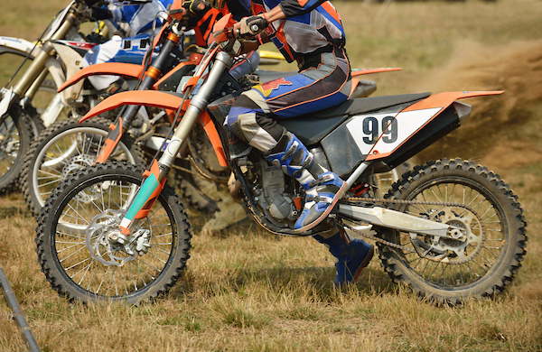 Dirt bikes racing off from a standing start in a field 
