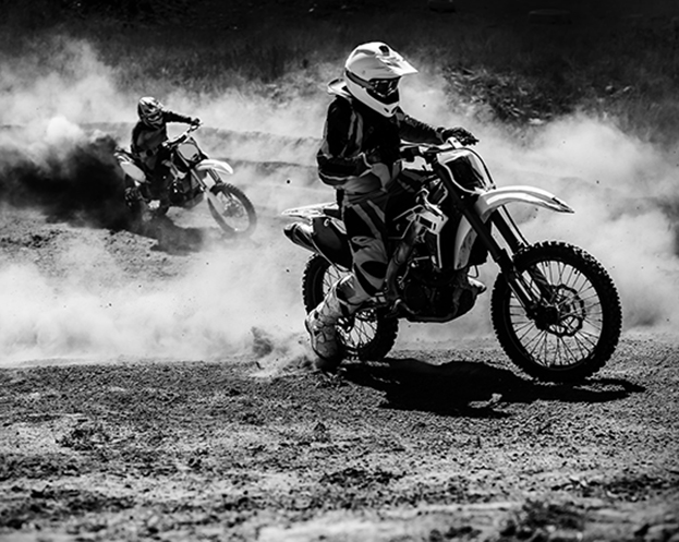 Motocross racer accelerating in dust track, Black and white, high contrast photo. 
