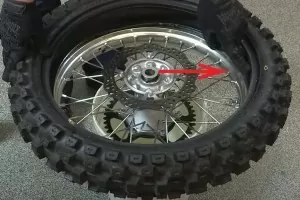 Dirt bike tire close-up with arrow locating where to reinstall tube with valve core